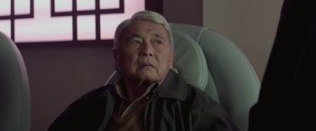 Movie still from “The Gambler” (2014), directed by Rupert Wyatt – An older man sitting in a chair looking at the camera; Close Up shot, Low angle