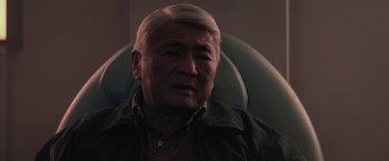 Movie still from “The Gambler” (2014), directed by Rupert Wyatt – An older man sitting in an office chair; Close Up shot, Over the shoulder angle