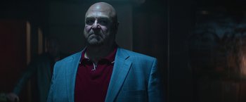 Movie still from “The Gambler” (2014), directed by Rupert Wyatt – A bald man in a blue jacket and a red shirt; Close Up shot, Low angle