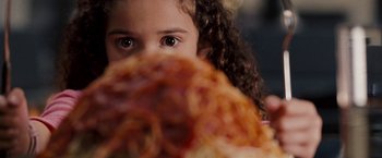 Movie still from “The Game Plan” (2007), directed by Andy Fickman – A little girl with curly hair is looking at a piece of pizza; Extreme Close Up shot, Over the shoulder angle