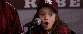 Movie still from “The Game Plan” (2007), directed by Andy Fickman – A girl with curly hair wearing a baseball cap is holding a microphone; Close Up shot, Low angle