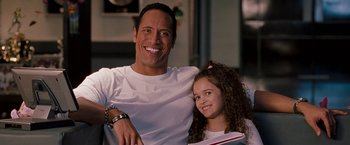 Movie still from “The Game Plan” (2007), directed by Andy Fickman – A man sitting next to a little girl holding a book; Close Up shot, Over the shoulder angle