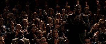 Movie still from “The Game Plan” (2007), directed by Andy Fickman – A group of people sitting in a dark room clapping; Wide shot, Low angle
