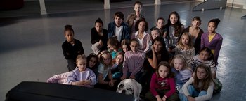 Movie still from “The Game Plan” (2007), directed by Andy Fickman – A group of people and a dog sitting in a room together; Wide shot, High angle