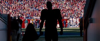Movie still from “The Game Plan” (2007), directed by Andy Fickman – A silhouette of a man in front of a crowd of people; Wide shot, Overhead angle