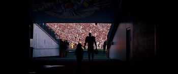 Movie still from “The Game Plan” (2007), directed by Andy Fickman – A man walking down a ramp towards a crowd; Extreme Wide shot, Over the shoulder angle
