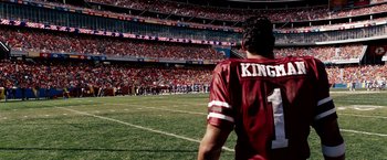 Movie still from “The Game Plan” (2007), directed by Andy Fickman – A man in a football uniform stands on a field; Medium shot, High angle