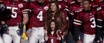 A woman and a girl are standing in front of a group of football players