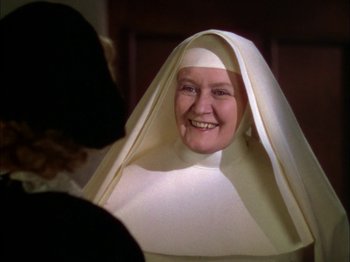 Movie still from “The Garden of Allah” (1936), directed by Richard Boleslawski – A woman in a nun's habit smiling at the camera; Close Up shot, Over the shoulder angle