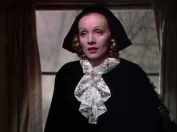 Movie still from “The Garden of Allah” (1936), directed by Richard Boleslawski – A woman wearing a black coat and a white hat; Close Up shot, Over the shoulder angle