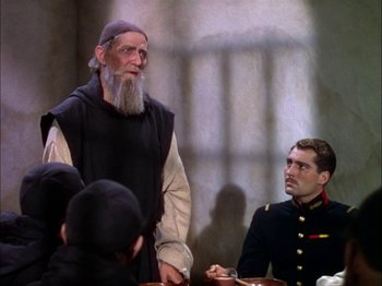 Movie still from “The Garden of Allah” (1936), directed by Richard Boleslawski – A man in a monk's outfit standing next to a man in a military uniform; Medium shot, Over the shoulder angle