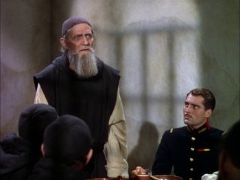 Movie still from “The Garden of Allah” (1936), directed by Richard Boleslawski – A man with a long beard standing next to a man in a uniform; Medium shot, Over the shoulder angle