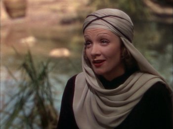 Movie still from “The Garden of Allah” (1936), directed by Richard Boleslawski – A woman wearing a headscarf standing next to a river; Close Up shot, Over the shoulder angle
