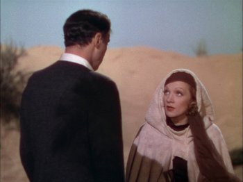 Movie still from “The Garden of Allah” (1936), directed by Richard Boleslawski – A man and a woman standing next to each other in the desert; Medium shot, Over the shoulder angle