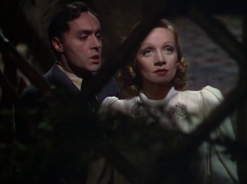 Movie still from “The Garden of Allah” (1936), directed by Richard Boleslawski – A man and a woman standing next to each other in front of a tree; Medium shot, Low angle