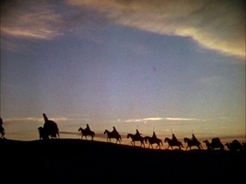 Movie still from “The Garden of Allah” (1936), directed by Richard Boleslawski – A group of people riding horses across a field; Extreme Wide shot, Low angle