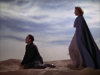 Movie still from “The Garden of Allah” (1936), directed by Richard Boleslawski – A man and a woman are sitting in the sand; Wide shot, Low angle