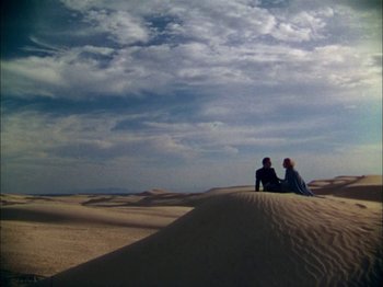 Movie still from “The Garden of Allah” (1936), directed by Richard Boleslawski – Two people sitting on top of a sand dune; Extreme Wide shot, High angle