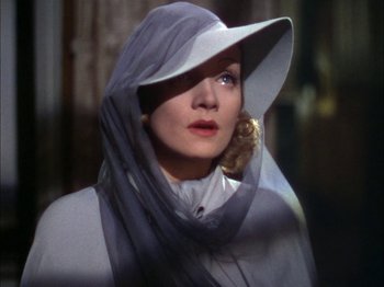 Movie still from “The Garden of Allah” (1936), directed by Richard Boleslawski – A woman in a white hat and a white dress; Close Up shot, Low angle