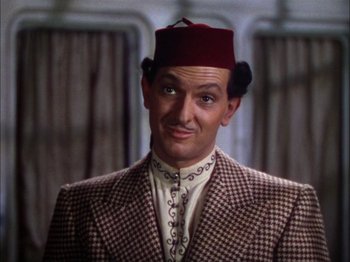 Movie still from “The Garden of Allah” (1936), directed by Richard Boleslawski – A person wearing a suit and a hat; Close Up shot, High angle