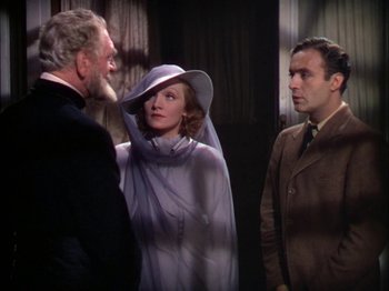 Movie still from “The Garden of Allah” (1936), directed by Richard Boleslawski – Two men and a woman standing next to each other in a room; Medium shot, Over the shoulder angle