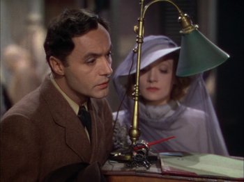 Movie still from “The Garden of Allah” (1936), directed by Richard Boleslawski – A man and a woman are sitting at a desk; Medium shot, Low angle