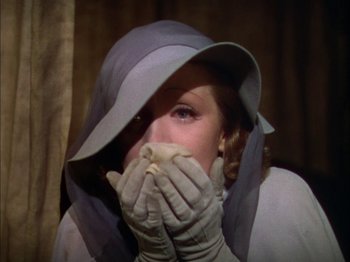 Movie still from “The Garden of Allah” (1936), directed by Richard Boleslawski – A woman in a hat and gloves covering her mouth; Close Up shot, High angle