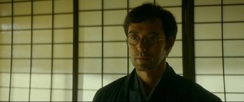 Movie still from “The Garden of Evening Mists” (2019), directed by Tom Lin – A man wearing glasses and a kimono; Close Up shot, Over the shoulder angle