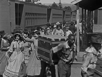 Movie still from “The General” (1926), directed by Buster Keaton – A black and white photo of a group of people walking down a street; Wide shot, High angle