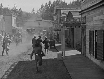 Movie still from “The General” (1926), directed by Buster Keaton – A black and white photo of men on horseback in a town; Extreme Wide shot, Low angle