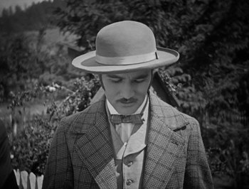 Movie still from “The General” (1926), directed by Buster Keaton – A black and white photo of a man wearing a suit and a hat; Close Up shot, High angle
