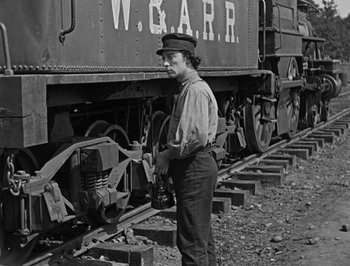 Movie still from “The General” (1926), directed by Buster Keaton – A woman standing next to a train on the train tracks; Medium shot, Low angle