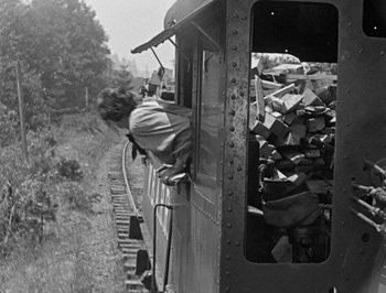 Movie still from “The General” (1926), directed by Buster Keaton – An old black and white photo of a man riding a train; Wide shot, Low angle