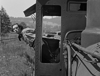 Movie still from “The General” (1926), directed by Buster Keaton – A man standing on the side of a train looking out of the window; Medium shot, Low angle