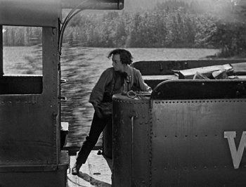 Movie still from “The General” (1926), directed by Buster Keaton – A man standing on a boat in the water; Wide shot, High angle