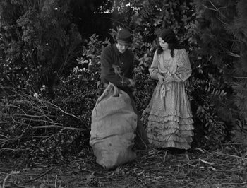Movie still from “The General” (1926), directed by Buster Keaton – A man and a woman standing next to each other in the woods; Wide shot, High angle