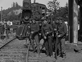 Movie still from “The General” (1926), directed by Buster Keaton – A black and white photo of a group of men standing next to each other; Wide shot, High angle