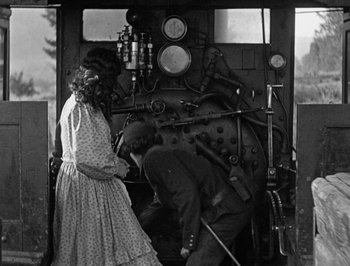 Movie still from “The General” (1926), directed by Buster Keaton – A woman and a man working on an engine; Medium shot, Low angle