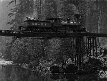 Movie still from “The General” (1926), directed by Buster Keaton – An old steam train crossing a bridge over a river; Extreme Wide shot, Low angle