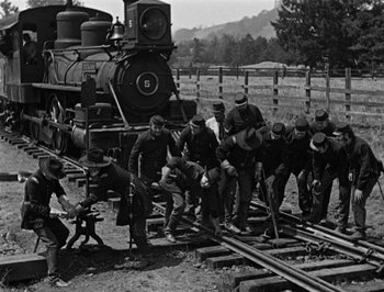 Movie still from “The General” (1926), directed by Buster Keaton – A black and white photo of a group of men working on a train track; Wide shot, High angle