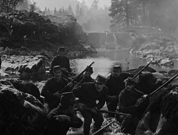 Movie still from “The General” (1926), directed by Buster Keaton – A black and white photo of a group of men with guns; Wide shot, High angle