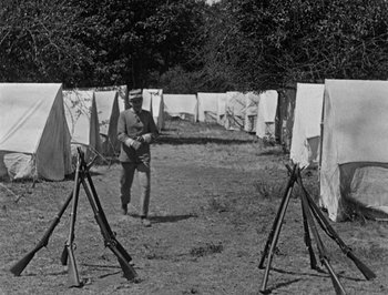 Movie still from “The General” (1926), directed by Buster Keaton – An old photo of a man standing in front of a line of clotheslines; Wide shot, High angle