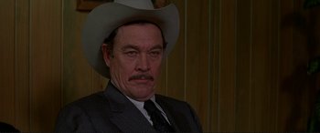 Movie still from “The Getaway” (1972), directed by Sam Peckinpah – A person wearing a suit and a cowboy hat; Close Up shot, Over the shoulder angle