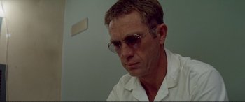 Movie still from “The Getaway” (1972), directed by Sam Peckinpah – A person wearing glasses and a white shirt; Close Up shot, Low angle