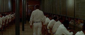 Movie still from “The Getaway” (1972), directed by Sam Peckinpah – A group of men sitting in a room with chairs; Wide shot, Over the shoulder angle