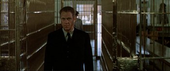 Movie still from “The Getaway” (1972), directed by Sam Peckinpah – A man wearing a suit and tie in a jail cell; Medium shot, Low angle
