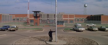 Movie still from “The Getaway” (1972), directed by Sam Peckinpah – A man standing next to a pole in a parking lot; Extreme Wide shot, Low angle