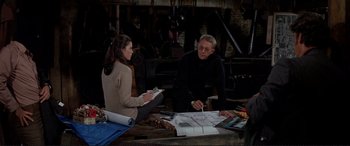 Movie still from “The Getaway” (1972), directed by Sam Peckinpah – A man and a woman sitting at a table with papers; Medium shot, Over the shoulder angle