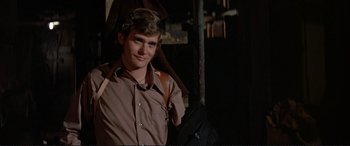 Movie still from “The Getaway” (1972), directed by Sam Peckinpah – A young man wearing a brown shirt and a black backpack; Close Up shot, Low angle