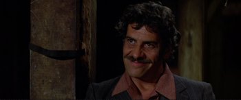 Movie still from “The Getaway” (1972), directed by Sam Peckinpah – A man with a mustache smiling for the camera; Close Up shot, Low angle